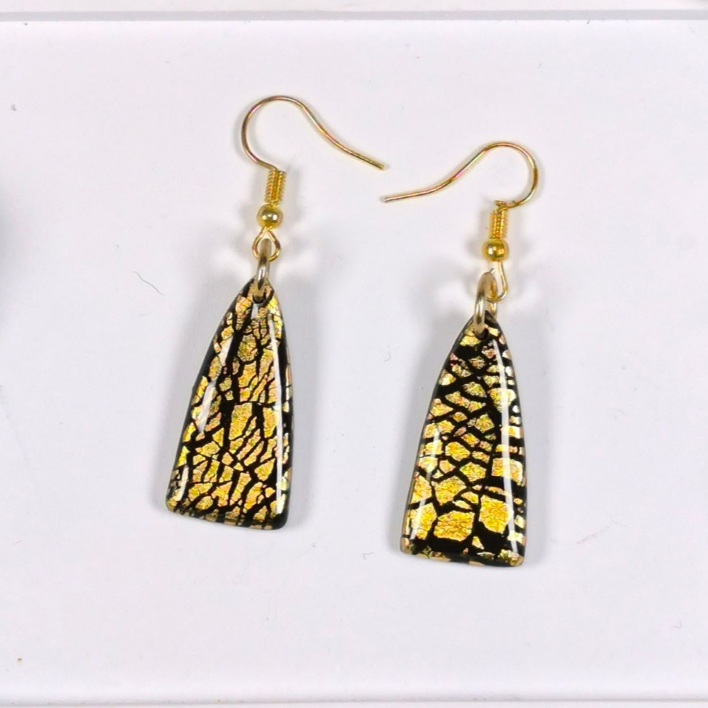 "Close-up of handmade black and gold earrings with UV resin finish and gold leaf"