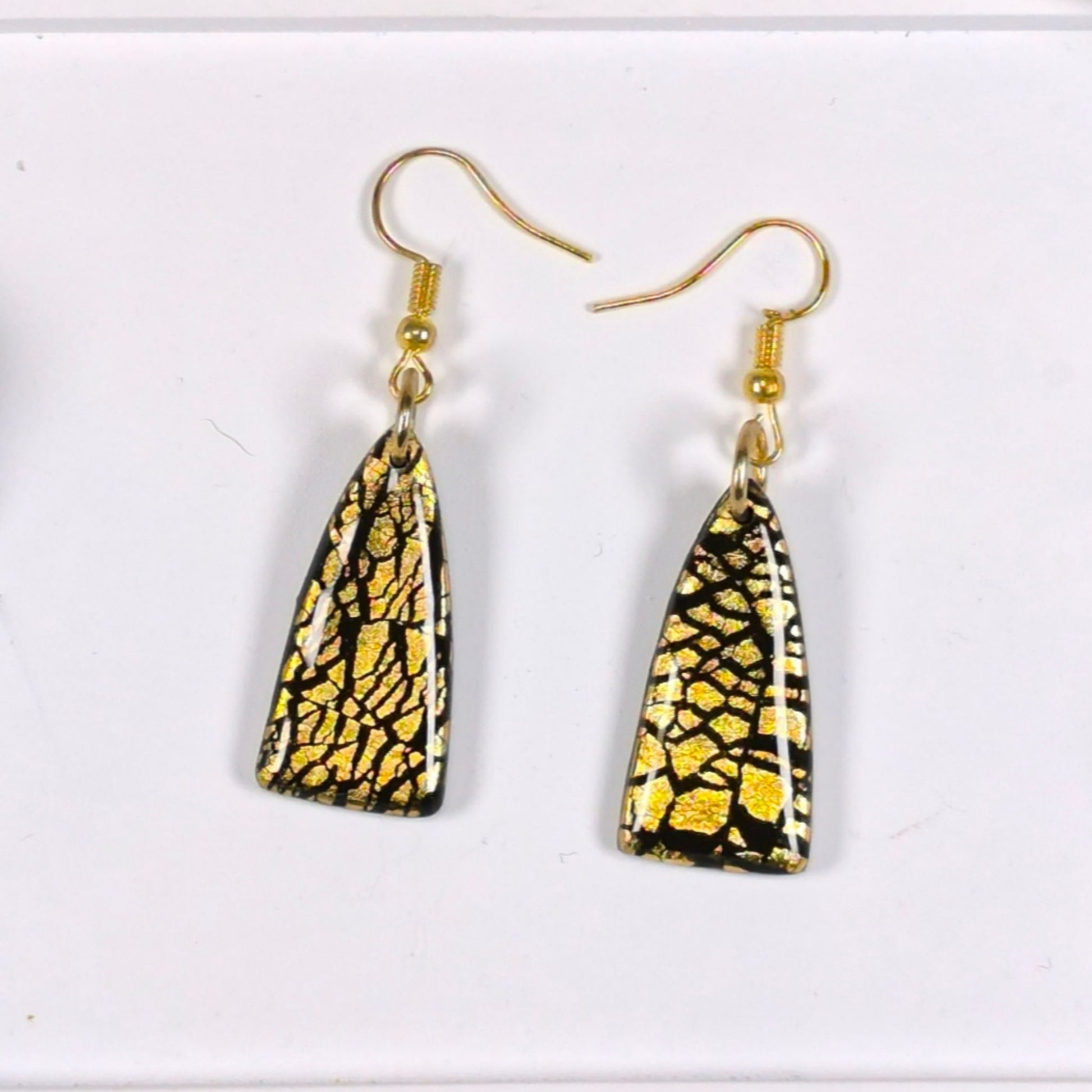 "Close-up of handmade black and gold earrings with UV resin finish and gold leaf"